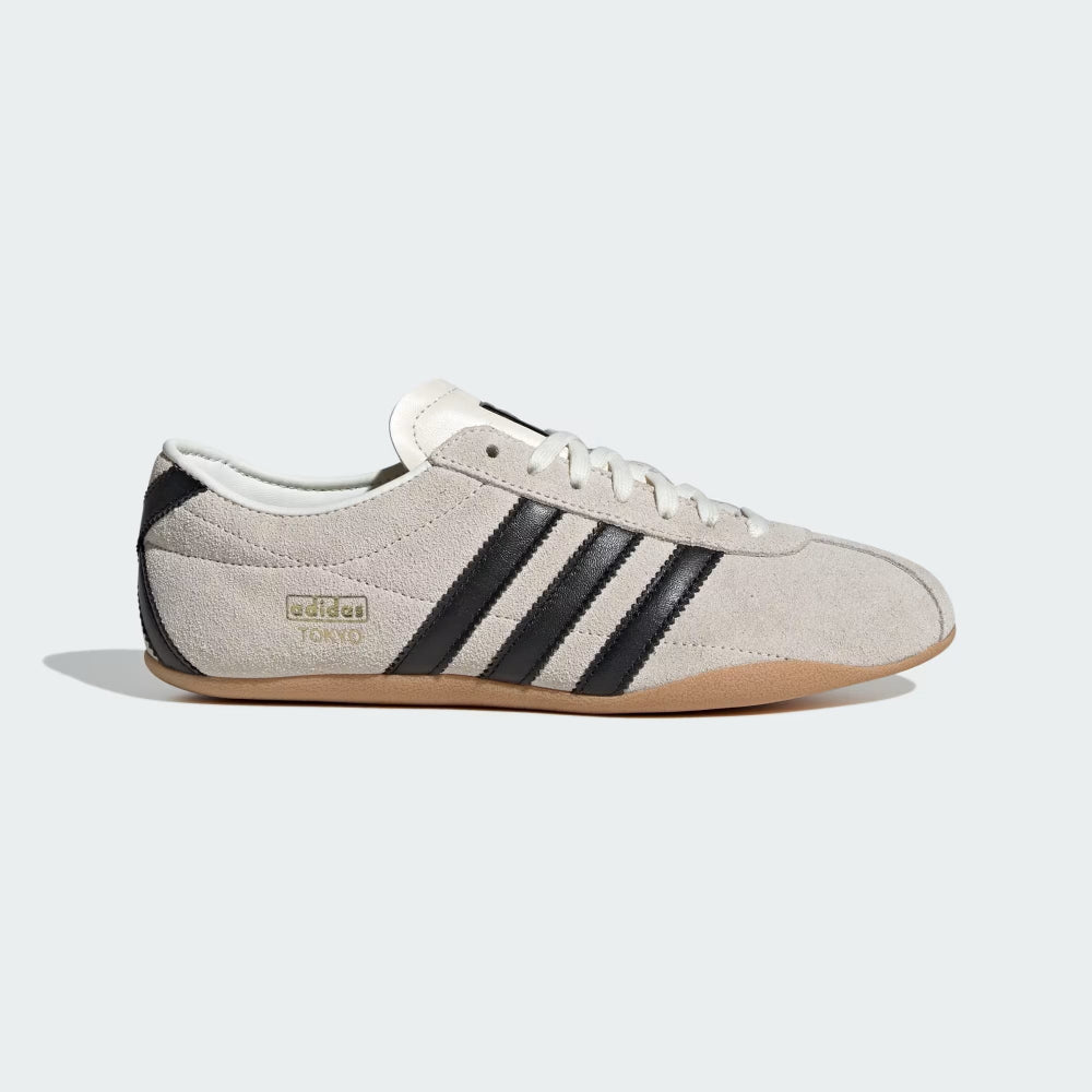Beige Adidas sneaker with black stripes on a white background